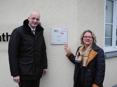 An der Rathauswand hängt die Plakette „Ort des Fortschritts“, die Bürgermeister Christoph Ewers und NRW-Wissenschaftsministerin Svenja Schulze enthüllten.