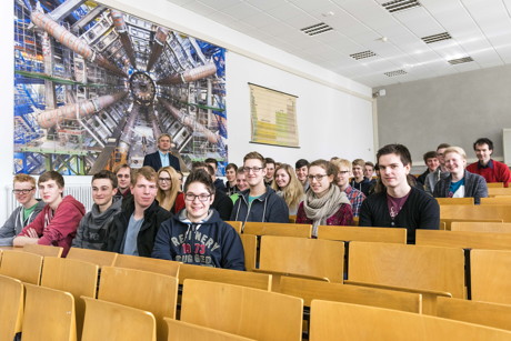 Schülerinnen und Schüler erlebten einen Tag an der Uni Siegen. Prof. Dr. Fleck leitete die „International Masterclasses“. Im Hintergrund ist ein Foto des Large Hadron Colliders (LHC) am CERN in der Schweiz zu sehen. (Foto: Uni)