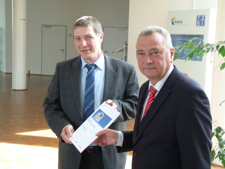 Econius-Geschäftsführer Dr. Hartmut Klein (links) übergibt den Zwischenbericht zu GET.Min an KM:SI-Geschäftsführer Reinhard Kämpfer. (Foto: KM:SI)