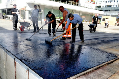 Beim Verteilen der 220 Grad Celsius heißen ersten Asphaltschicht geraten die Arbeiter auch bei kühleren Temperaturen auf der Siegbrücke ins Schwitzen. (Foto: Stadt)