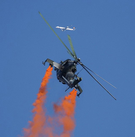 „Hirschkuh“ mit Durchfall: Die MIL-MI 24 der Tschechischen Luftwaffe untermalt ihre Vorführung mir orangfarbenem Rauch. Der Lufthansa-Airbus über dem mächtigen Helikopter hatte allerdings nichts mit der Airshow zu tun. (Foto: Werner Schmäing)