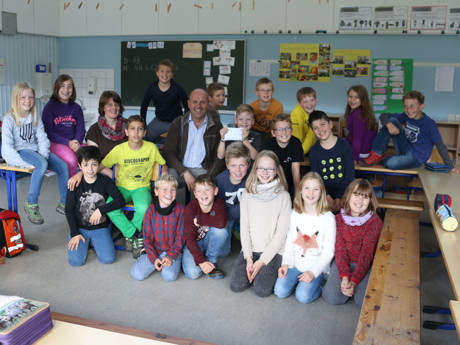 Die Schülerinnen und Schüler der vierten Klasse der Grundschule Struthütten, und Lehrerin Anne Capito (vierte von links) konnten Fachbereichsleiter Johannes Schneider (Mitte) jetzt einen Umschlag mit 187,- Euro überreichen. Das Geld soll Flüchtlingskindern zugutekommen. (Foto: Gemeinde Neunkirchen)