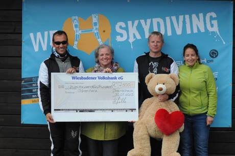 Während Thomas Schönecker (zweiter von rechts), der Schäuble von Springwerk, das Bärenherz-Maskottchen würgt, beglückte Sebastian Lauber (links), der Initiator des Tandem-Charity-Events, Stiftungs-Geschäftsführerin Anja Eli Klein mit einem über 2500 EUR ausgestellten Riesenscheck. Die gleiche Summe hat das Hilfswerk "Fly & Help" bereits erhalten. Rechts Vorstandsmitglied Kerstin Müller. (Fotos: Skydive Westerwald)