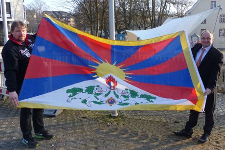 Bürgermeister Holger Menzel und sein Mitarbeiter Karsten Valenta (links) präsentieren vor dem Hissen die Flagge Tibets am Marktplatz. Foto: Stadt Hilchenbach