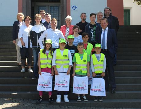 Sie tragen dazu bei, dass andere Kinder sicher zur Schule und nach Hause kommen: Die Schülerlotsen und Busbegleiter freuen sich über ihre Urkunden. Foto: Stadt Siegen