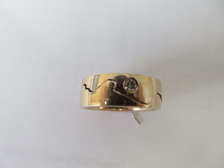 Bei dem Ring handelt es sich um einen goldenen, teilbaren Ehering mit eingearbeitetem Brillant. Auf der Innenseite sind der Name „Kans“ oder „Hans“ und das Datum „21. Juni 14“ eingraviert.