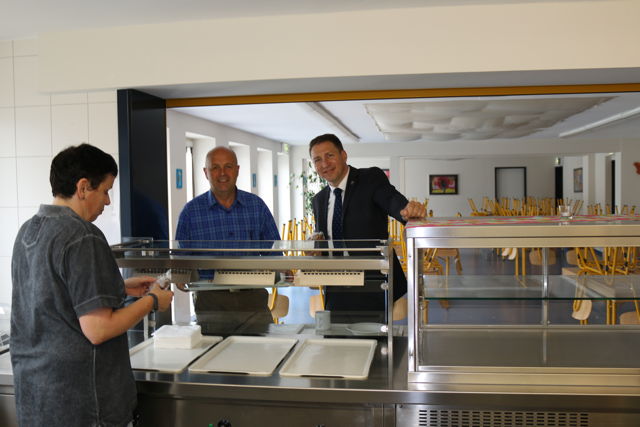 Fachbereichsleiter Johannes Schneider (Mitte) und Bürgermeister Bernhard Baumann statten der Mensa der Gemeinschaftlichen Sekundarschule Burbach-Neunkirchen am Standort Neunkirchen einen Besuch ab. Hier werden mit Beginn des neuen Schuljahres täglich mehr als 70 Essen über die Theke gehen. (Foto: Gemeinde Neunkirchen)